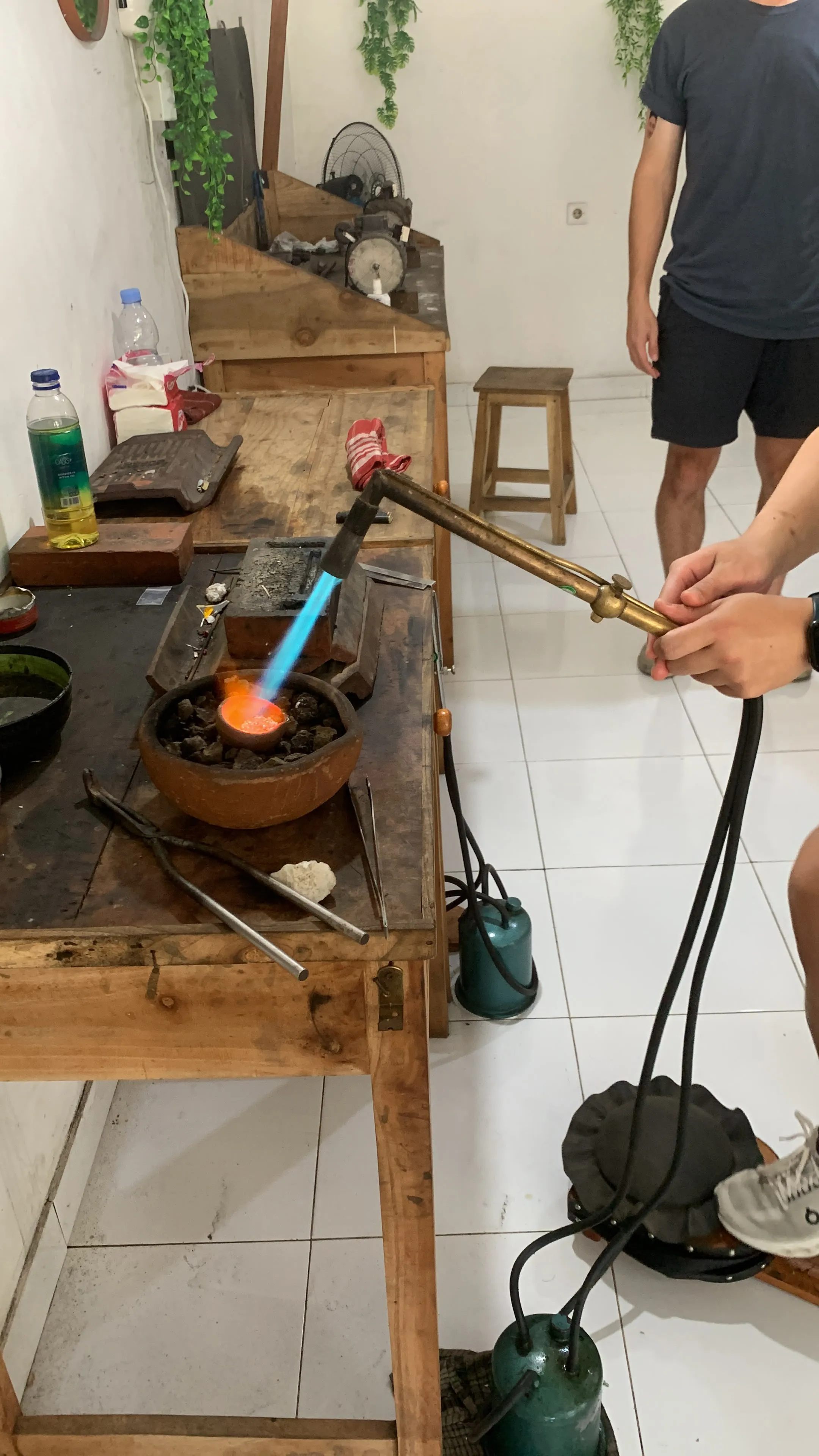 A participant heating silver in a crucible with a torch